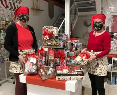 Kuvassa TaitoShopin myyjät maskeissaan esittelevät jouluisia lahjapakkauksia viihtyisässä myymälässä.