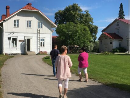 Kartanomajoitus Sofia&Angelique esittelyssä kesäpäivänä, etualalla vieras sekä omistajapariskunta kauniissa auringonpaisteessa kävelevät Pohjola-rakennusta kohti.