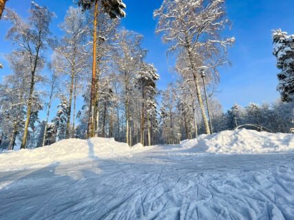 Pieksämäen Hiekanpään puistoluistelurata upeassa talvisessa auringonpaisteessa, etualalla luistinten jälkiä, taaempana kuuraisia mäntyjä ja koivuja.